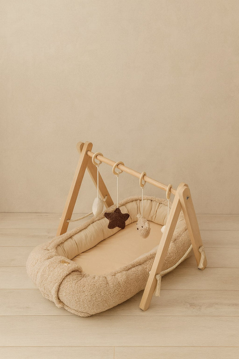 Babynestje teddy met houten babygym in een lichte babykamer
