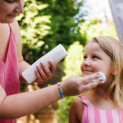 Moeder maakt de arm van haar kind schoon met een washandje van de rol