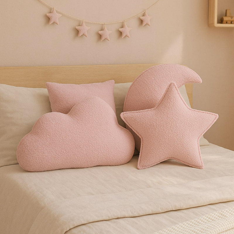 Roze sierkussens in ster- en wolkvorm op een bed