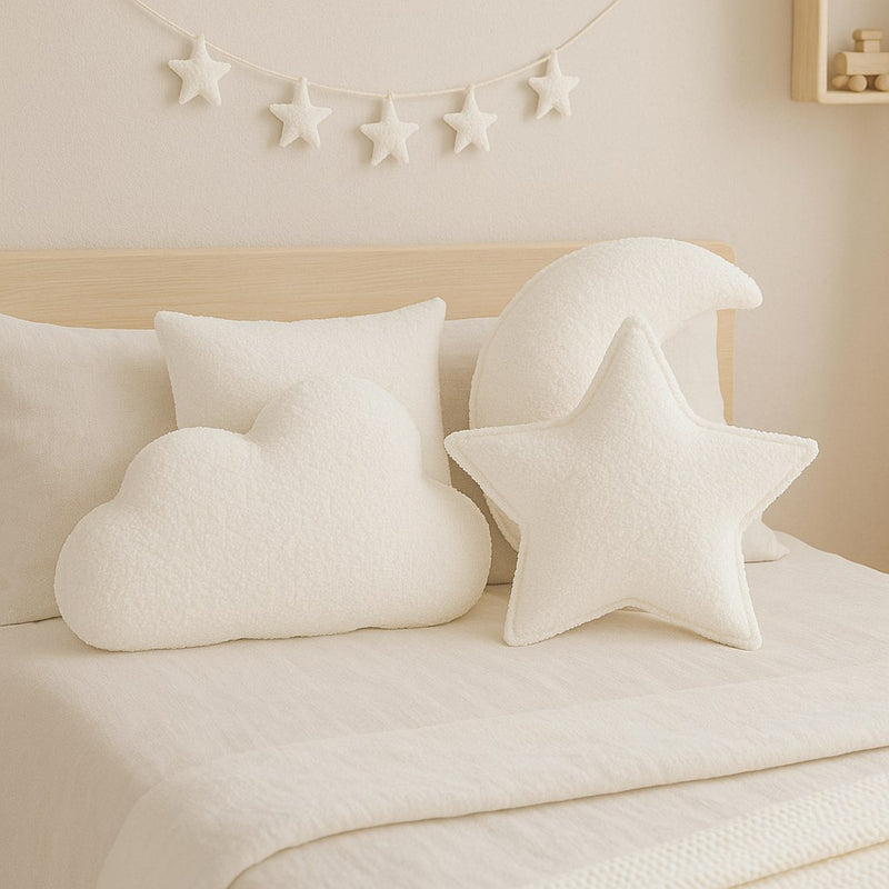 Witte sierkussens in wolk- en sterrenvorm op een bed